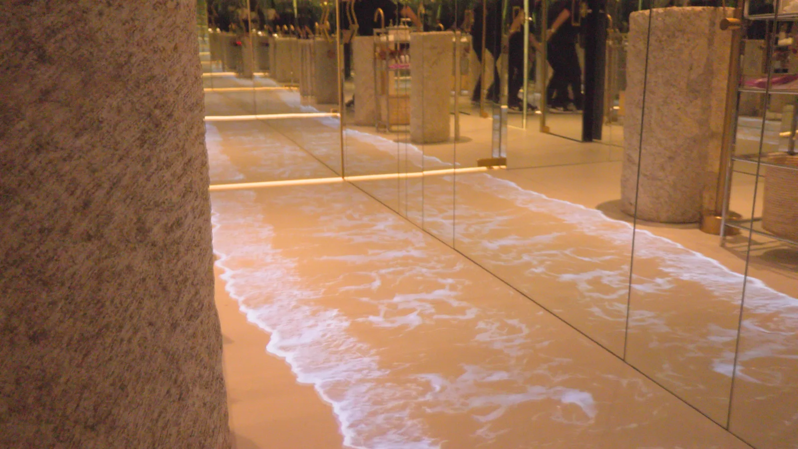 Banheiro com efeito praia, piso com onda e colunas de granito iluminadas